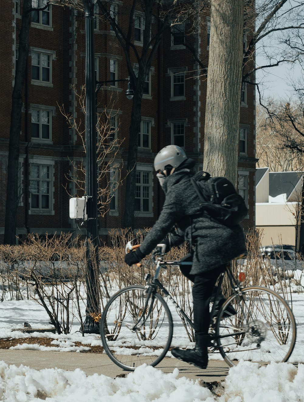 Persona in giacca nera che va in bicicletta su terreno coperto di neve durante il giorno