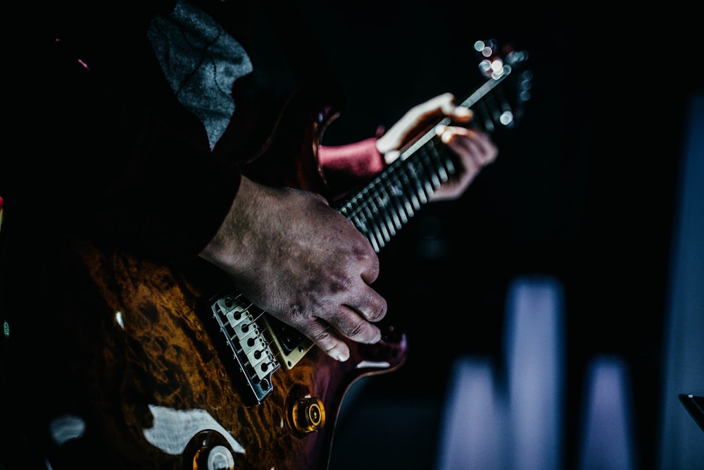 person playing brown and white stratocaster electric guitar