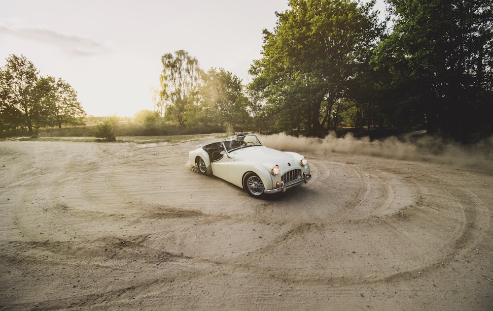 white coupe on dirt road during daytime