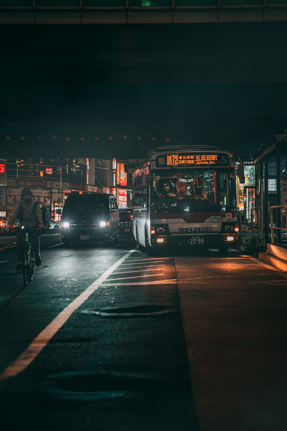 夜間の道路を走る赤い2階建てバス