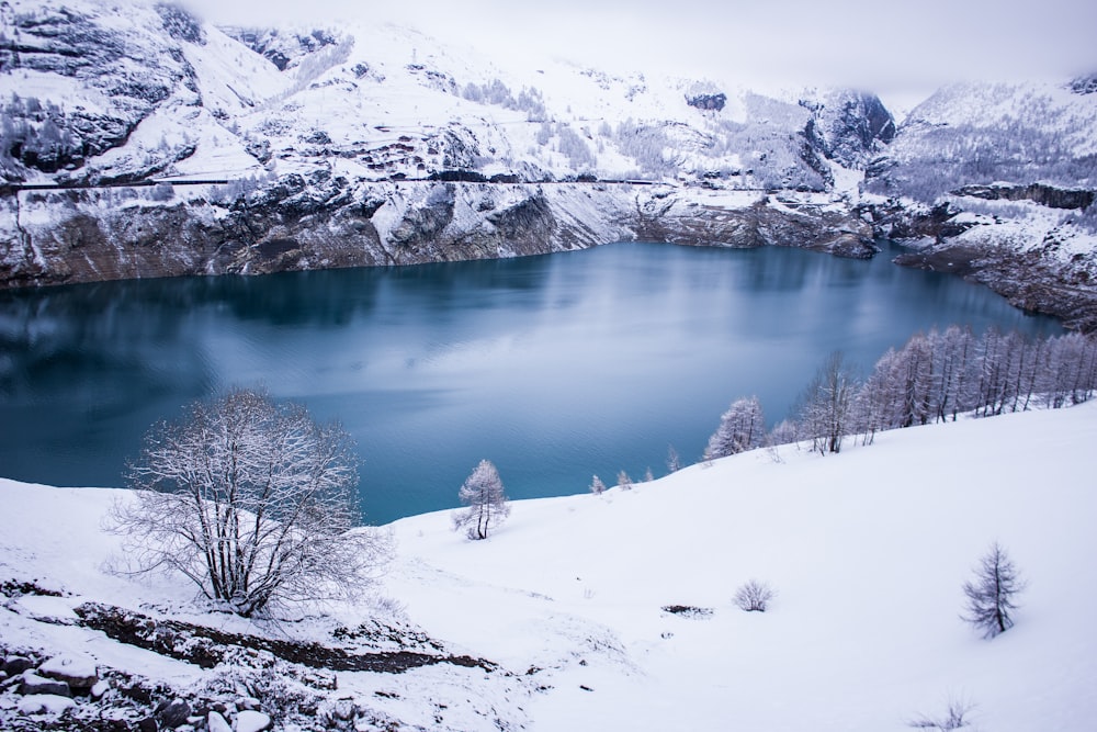 lake in the middle of snow covered mountains