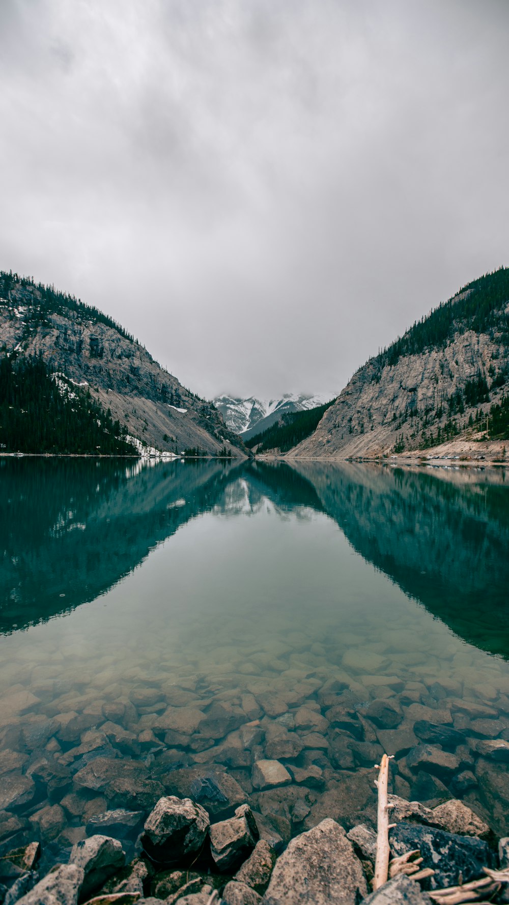 lake near mountain under cloudy sky during daytime