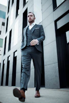 Man confidently walking in a charcoal gray suit with subtle rose gold cufflinks.