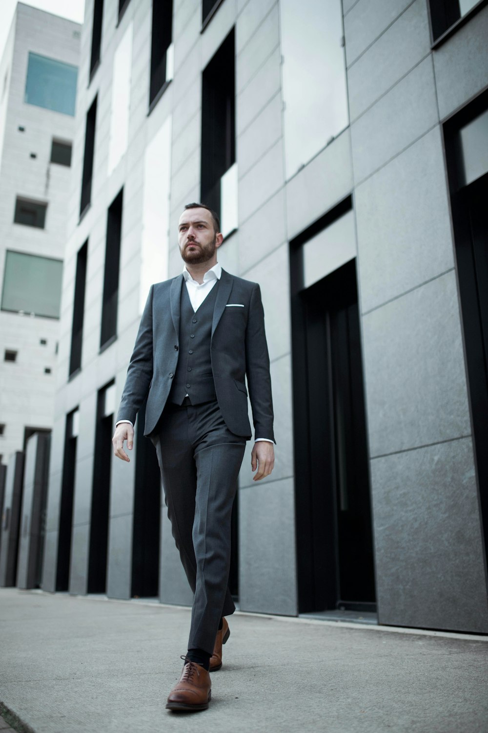 man in black suit standing near black metal gate during daytime