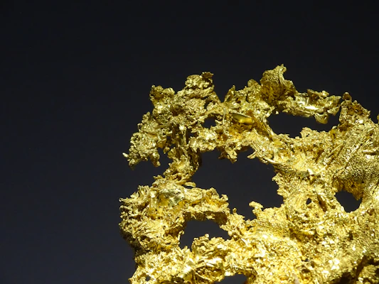 Close-up of a sleek gold detector resting on rocky terrain, sunlight glinting off its metallic surface.