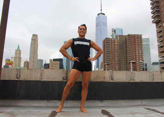 A confident individual standing tall, smiling with a city skyline behind.