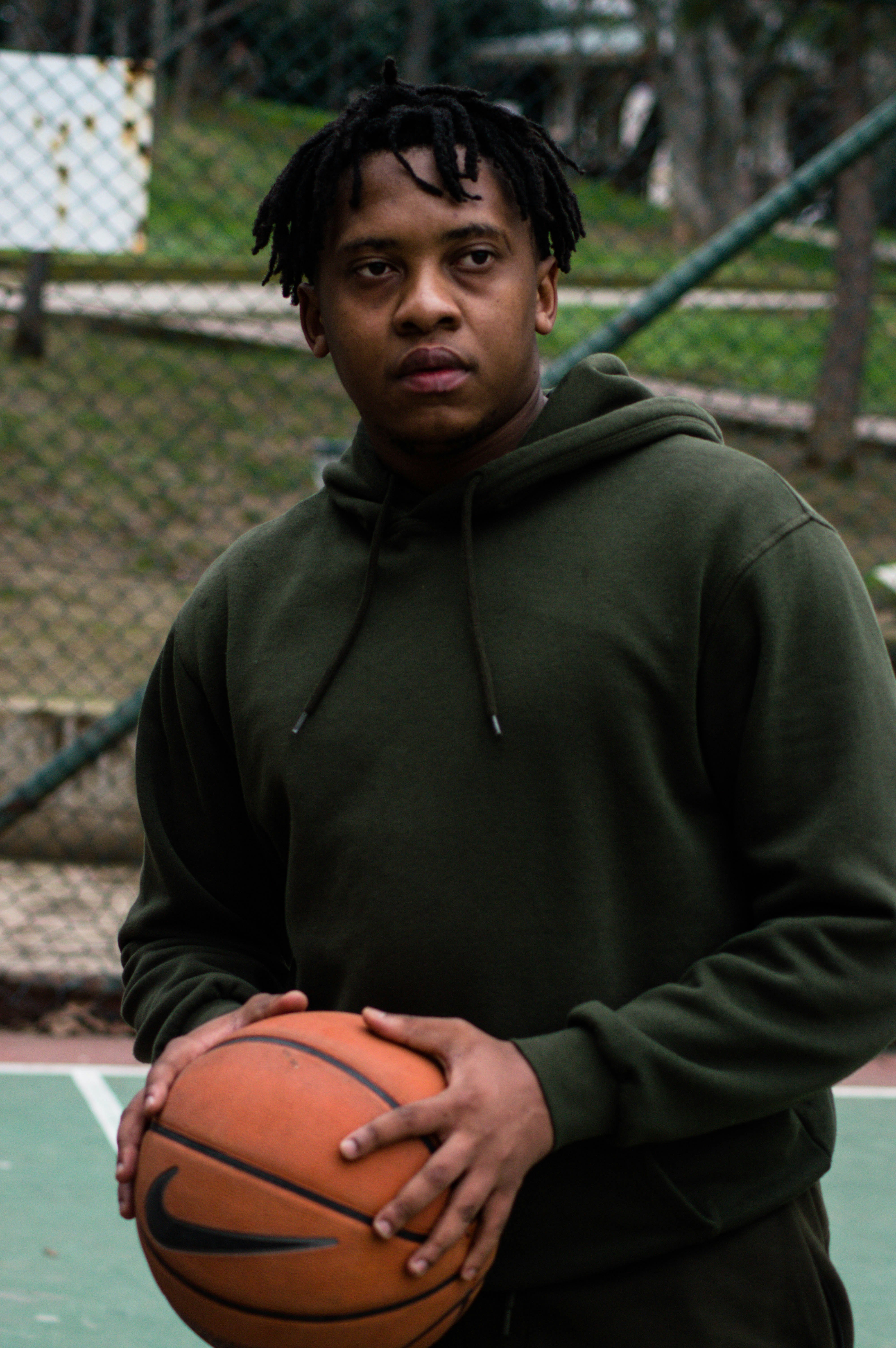 man in green hoodie holding basketball
