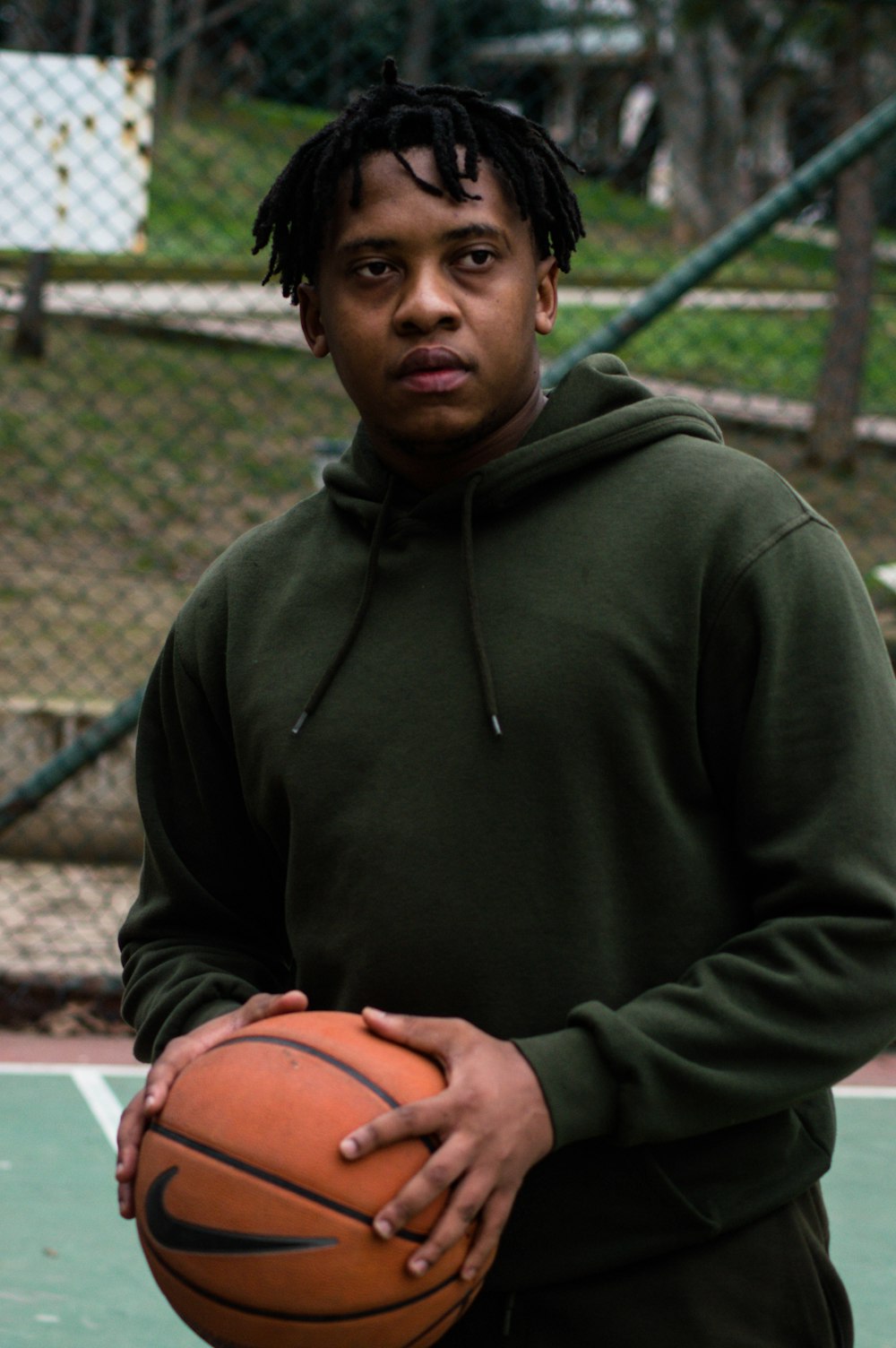 man in green hoodie holding basketball