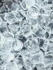A pile of clear cylindrical ice cubes with light reflecting off their surfaces