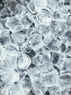 A pile of clear cylindrical ice cubes with light reflecting off their surfaces