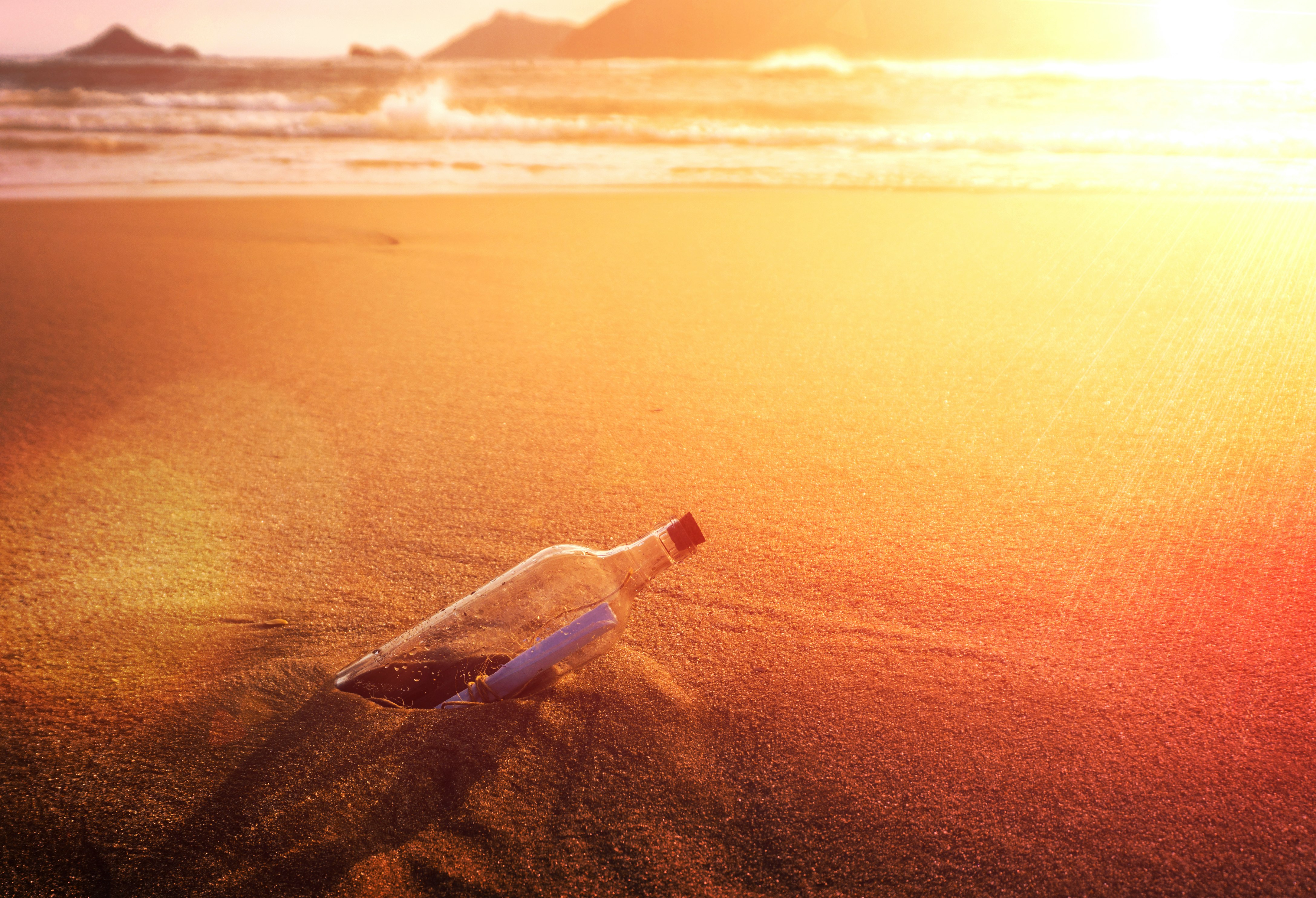 clear glass bottle on brown sand during daytime