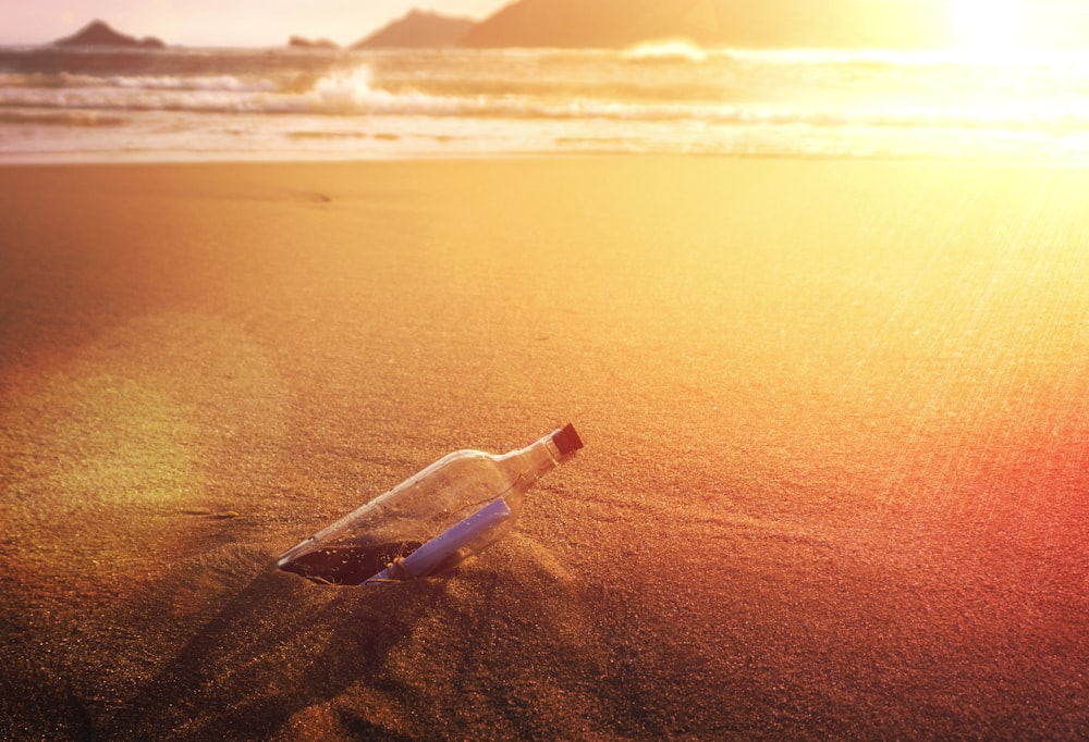 clear glass bottle on brown sand during daytime