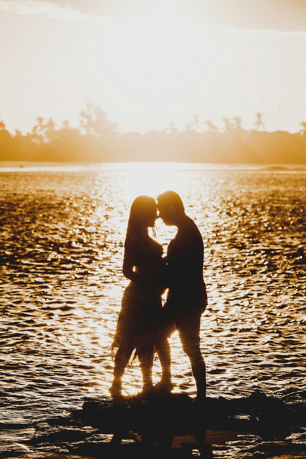 silhouette of woman and child on water during sunset