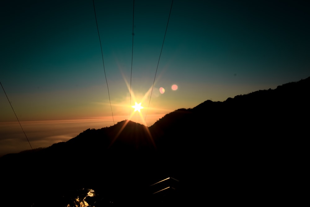 the sun is setting over a mountain range