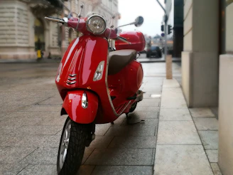 A vibrant red scooter cruising through a lively city street.