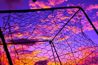 Close-up of a soccer ball hitting the net during a decisive goal at sunset.