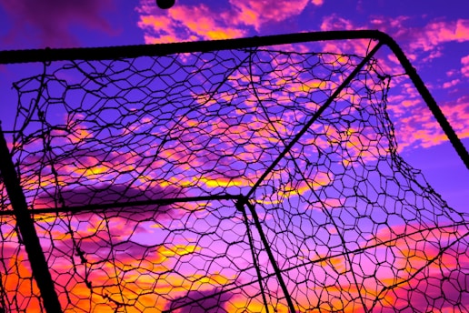 Close-up of a soccer ball hitting the net during a decisive goal at sunset.