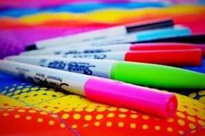 A collection of dot markers and bingo markers in various vivid colors scattered artistically.