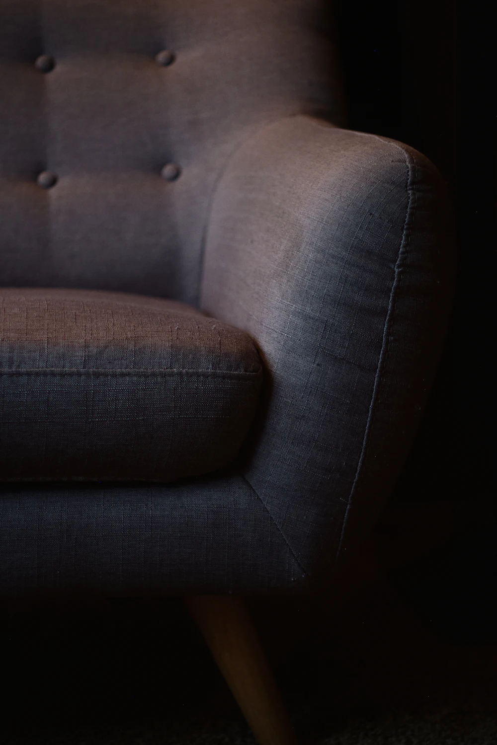 A cushioned armchair against a dark background
