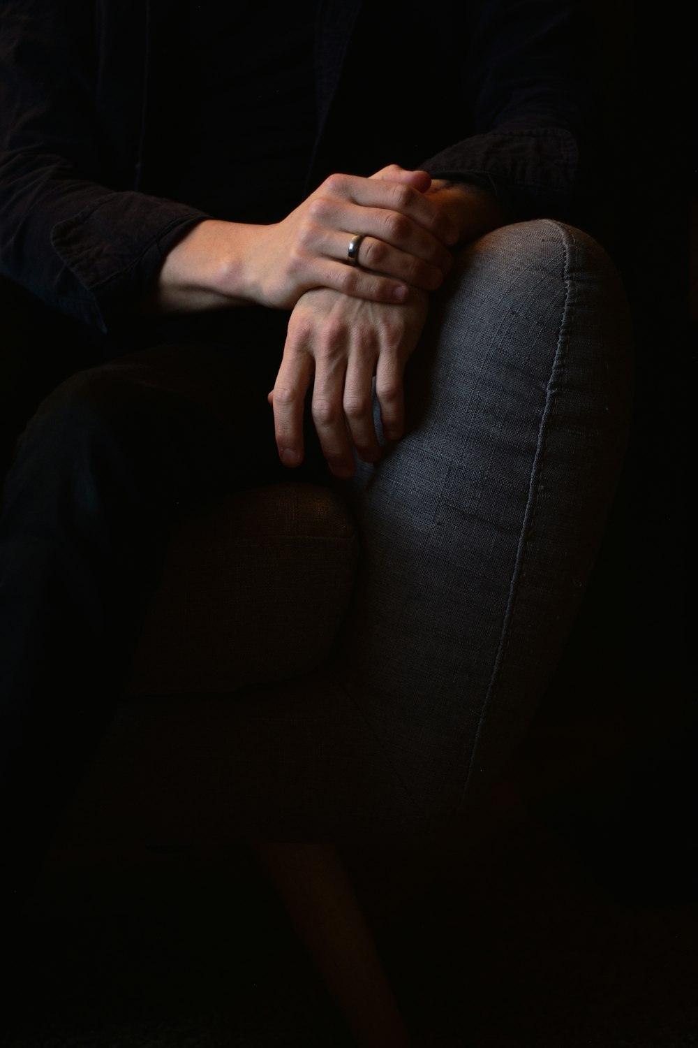 Person in schwarzer Hose sitzt auf grauer Couch