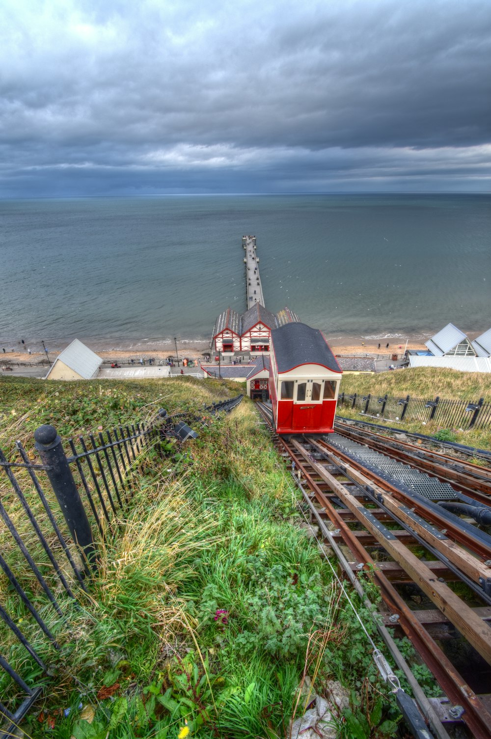 red and white train on rail near body of water during daytime