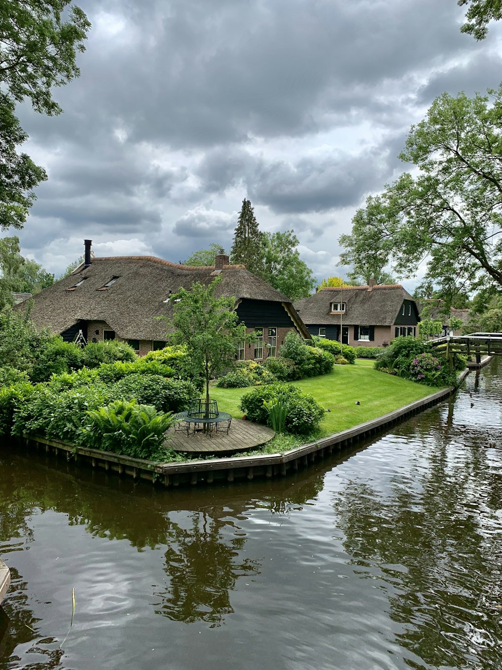 brown wooden house beside green trees and river during daytime