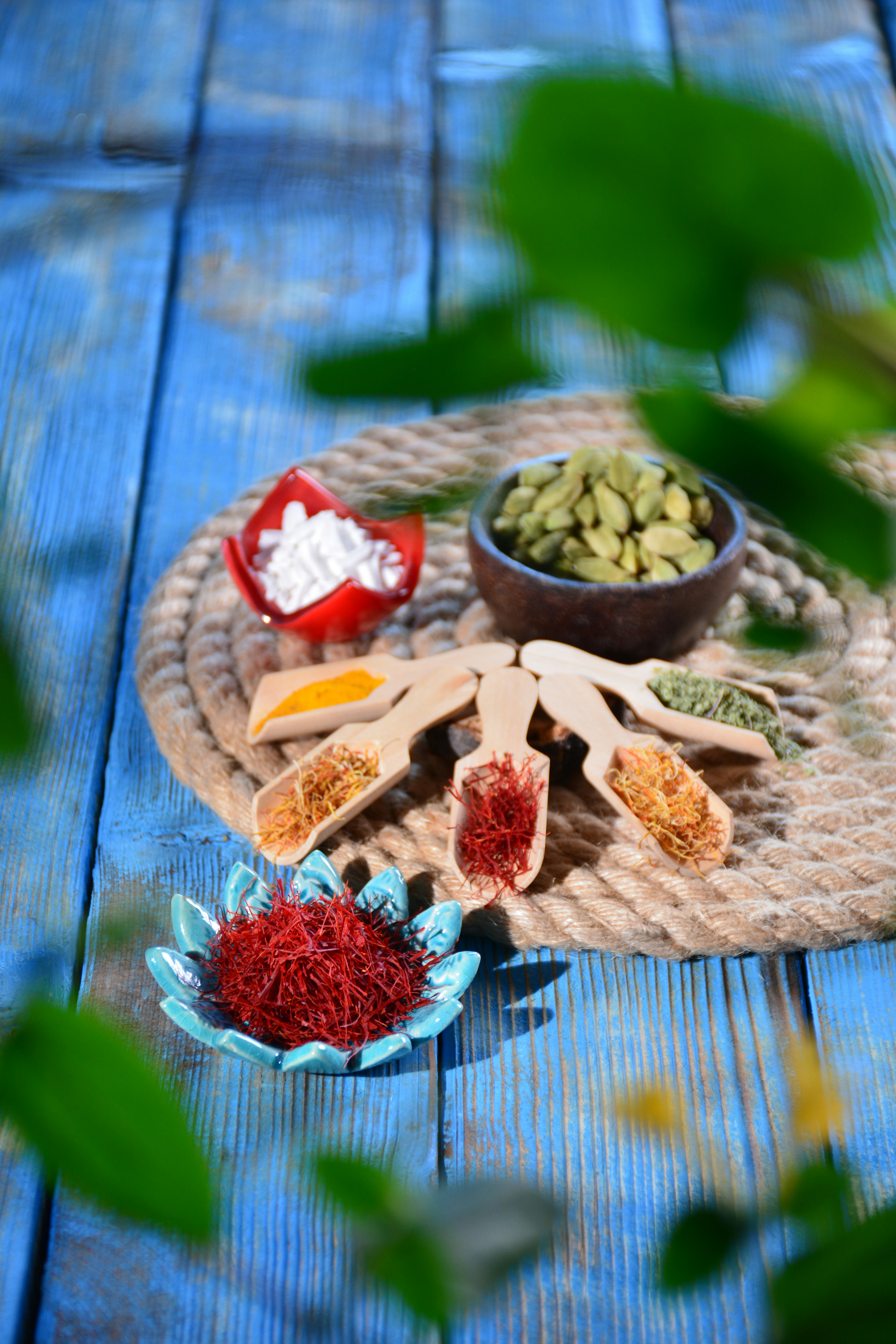 Colorful aromatic spices in wooden bowls — turmeric, cardamom, cloves, saffron — rich warm tones