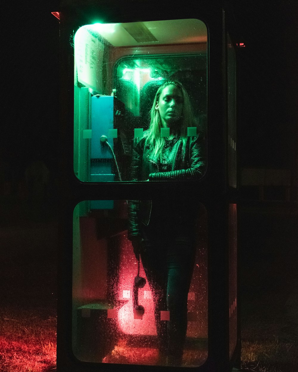 woman in black pants standing in front of green light