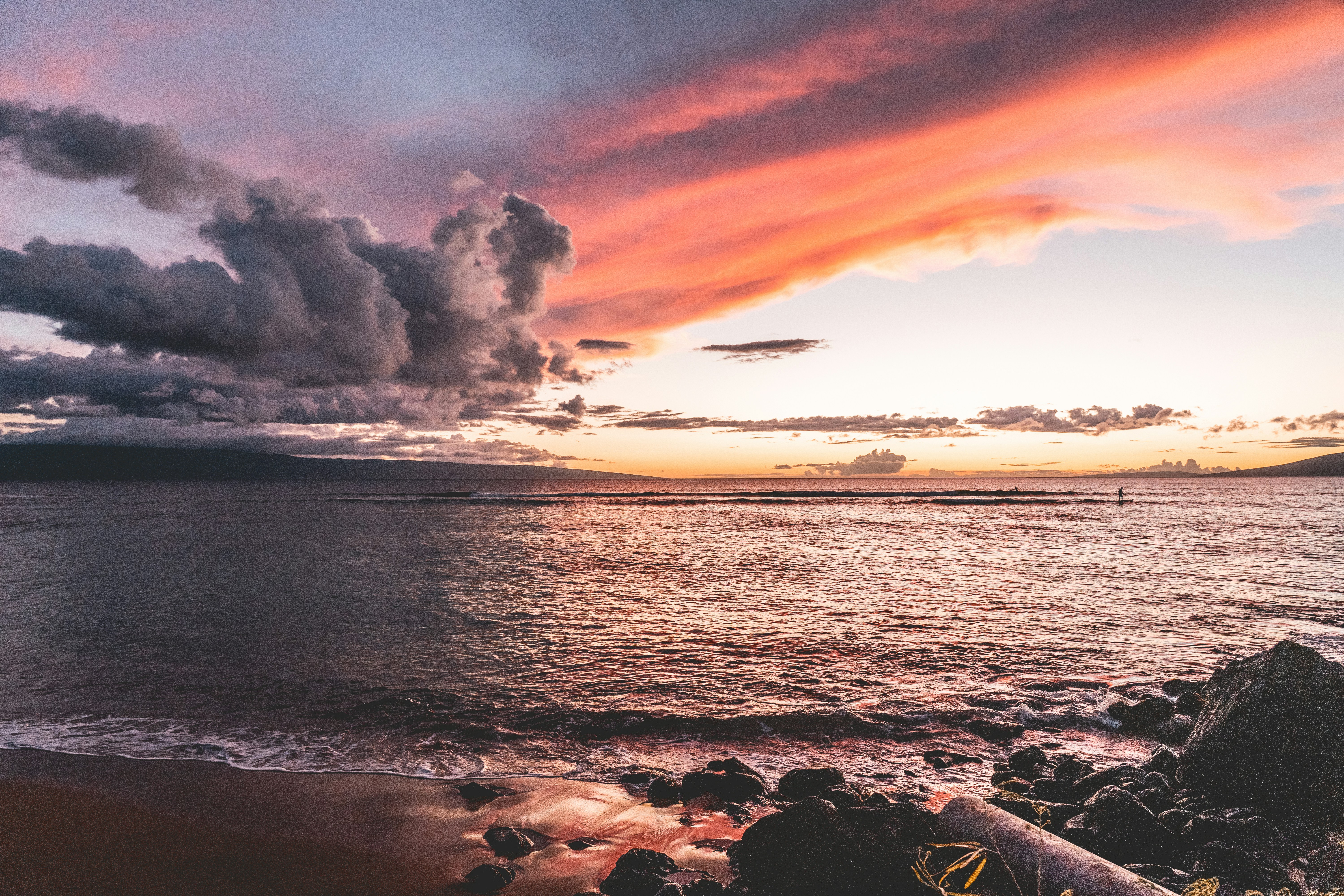 sea waves crashing on rocks under cloudy sky during sunset