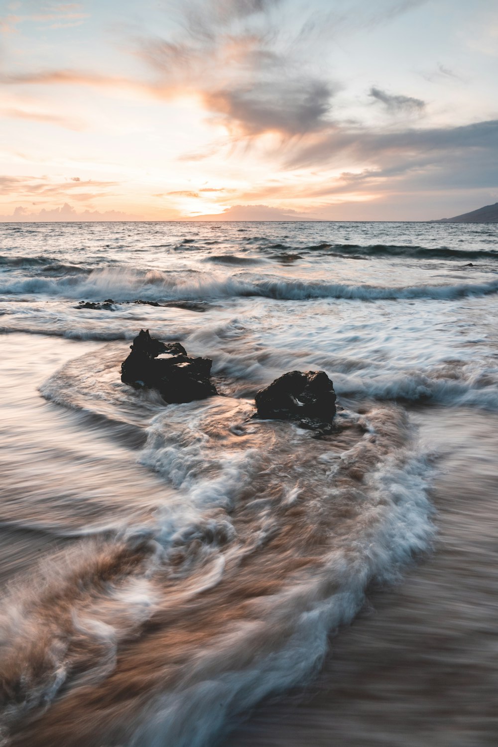 ocean waves crashing on rocks during sunset