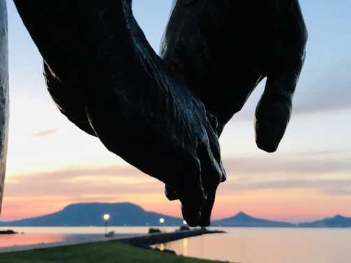 Hands gently holding a symbolic keepsake against a backdrop of Bay Area hills at dusk.