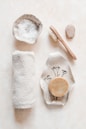 A vibrant flat lay of cold-pressed soaps, body oils, and bath bombs arranged on a wooden surface with soft natural light.