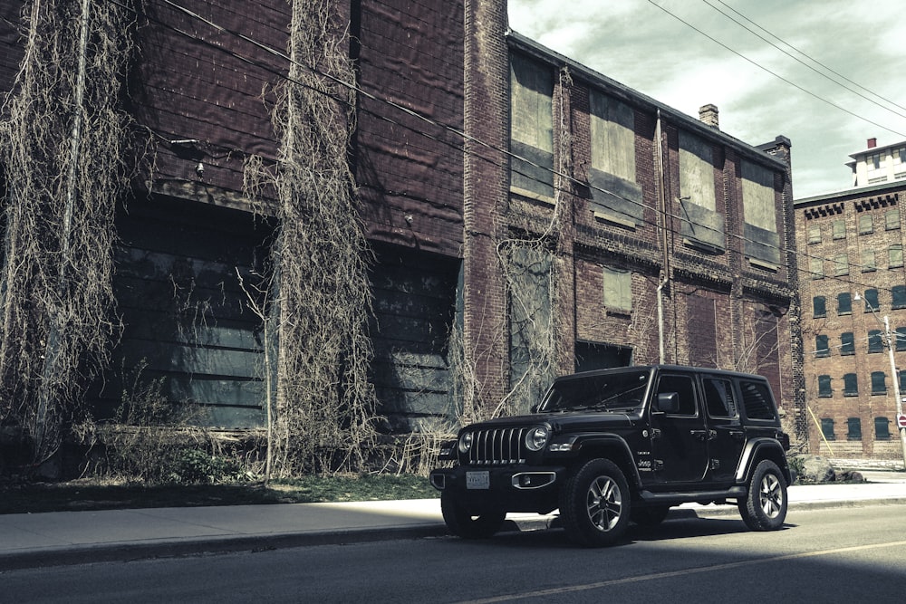 Jeep Wrangler noire garée à côté d’un bâtiment en briques brunes