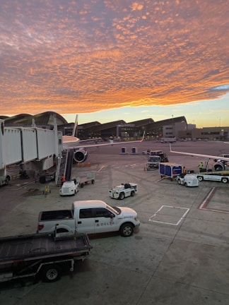 Airplane being loaded with freight at an airport during sunset.