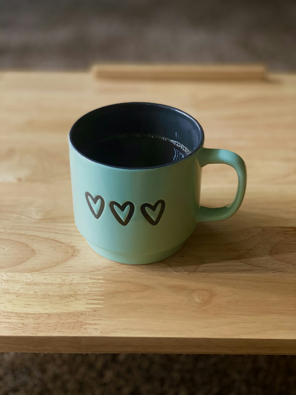 white and green ceramic mug on brown wooden table