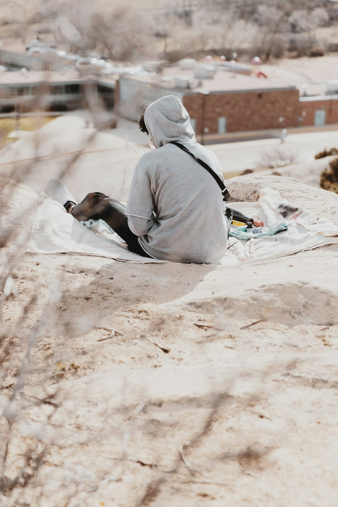 person in gray hoodie sitting on brown sand during daytime