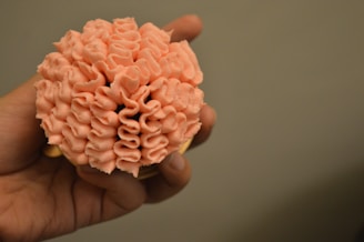 A hand holding a layered cup cake with a soft pastel background and gentle natural light.