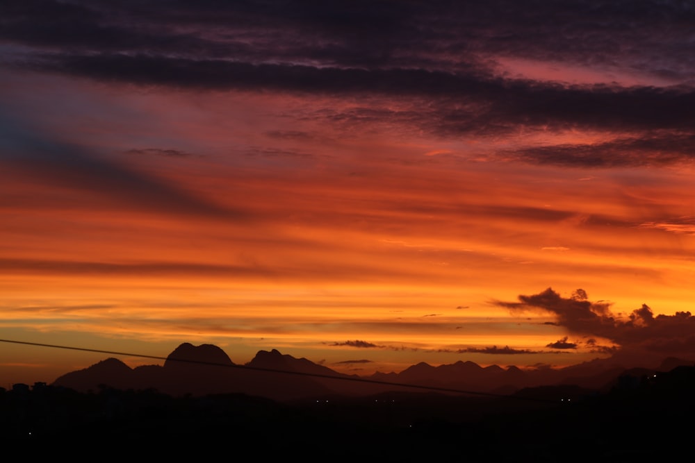 a sunset with clouds and mountains in the background