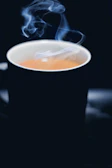 Close-up of a freshly brewed cup of coffee with steam rising in a modern office setting.