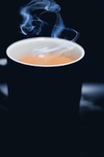 Close-up of a steaming cup of dark coffee with ghostly mist swirling above it.
