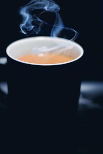 Elegant black coffee cup with golden steam rising against a dark background.