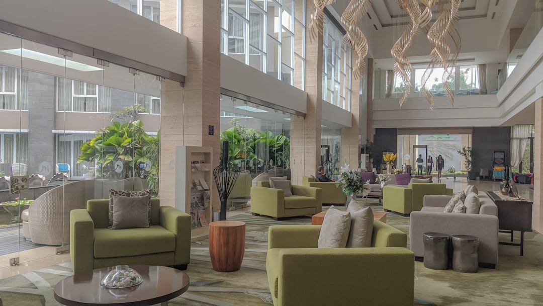 beige sofa set near green potted plant, Grand Mercure Bandung at Lobby area. Stunning lobby at beautiful hotel.