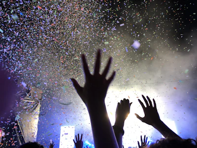 Crowd hands raised in excitement as the DJ cues the next track at a vibrant celebration.