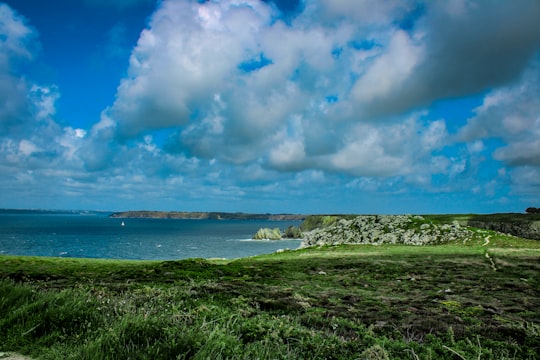 green grass field near body of water under blue and white cloudy sky during daytime in Crozon France