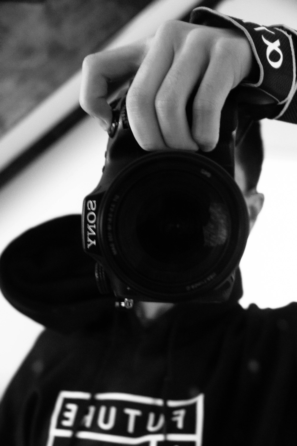 grayscale photo of person holding nikon dslr camera