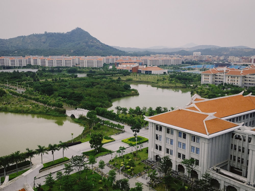 white and brown concrete building near green trees and body of water during daytime