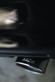 A close-up of a metallic exhaust pipe with a shiny surface, reflecting light and showing the brand logo imprinted on it. The background appears blurred, emphasizing the focus on the exhaust.
