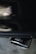 A close-up of a metallic exhaust pipe with a shiny surface, reflecting light and showing the brand logo imprinted on it. The background appears blurred, emphasizing the focus on the exhaust.