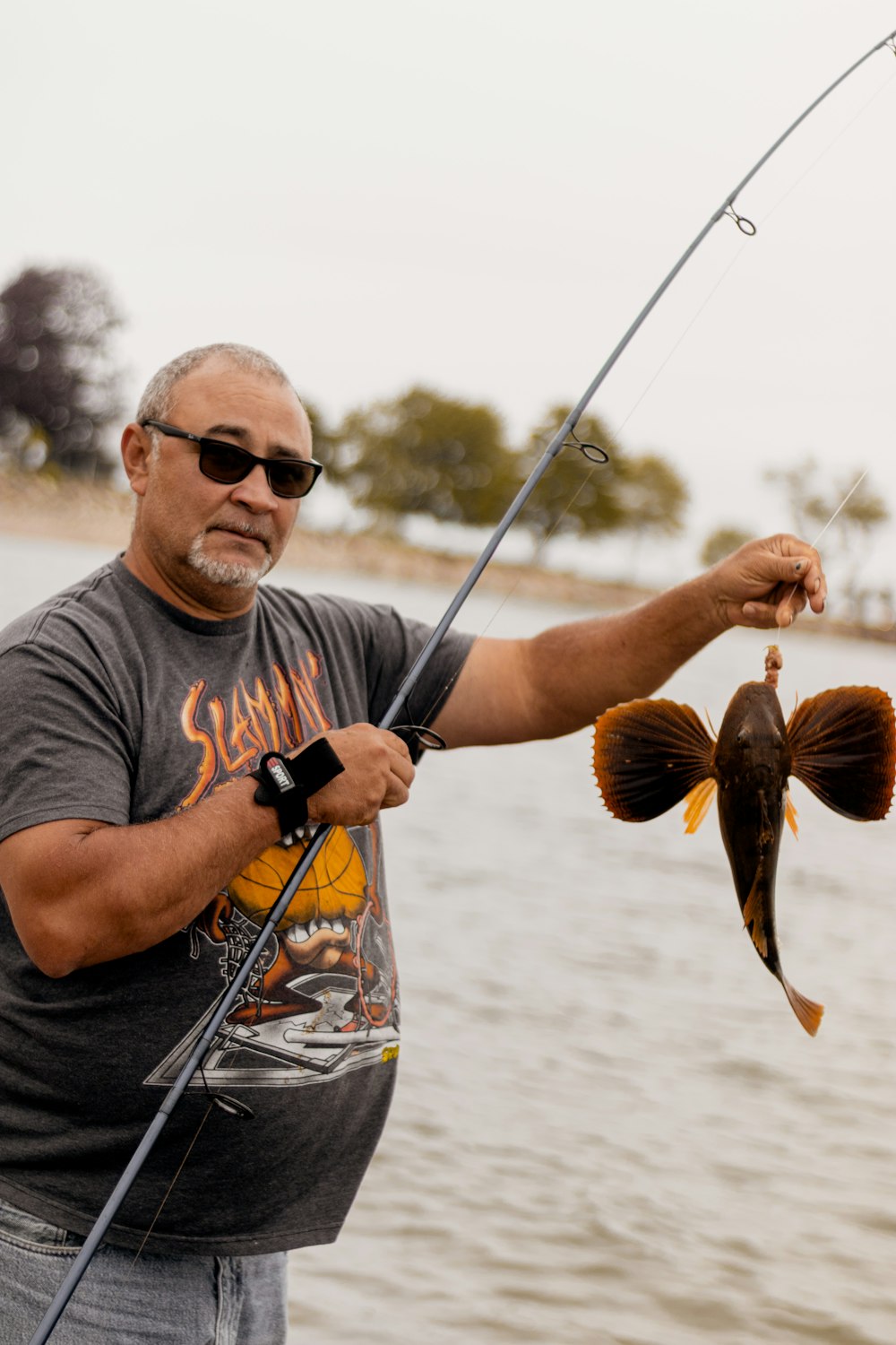 man in gray crew neck t-shirt holding brown fish during daytime