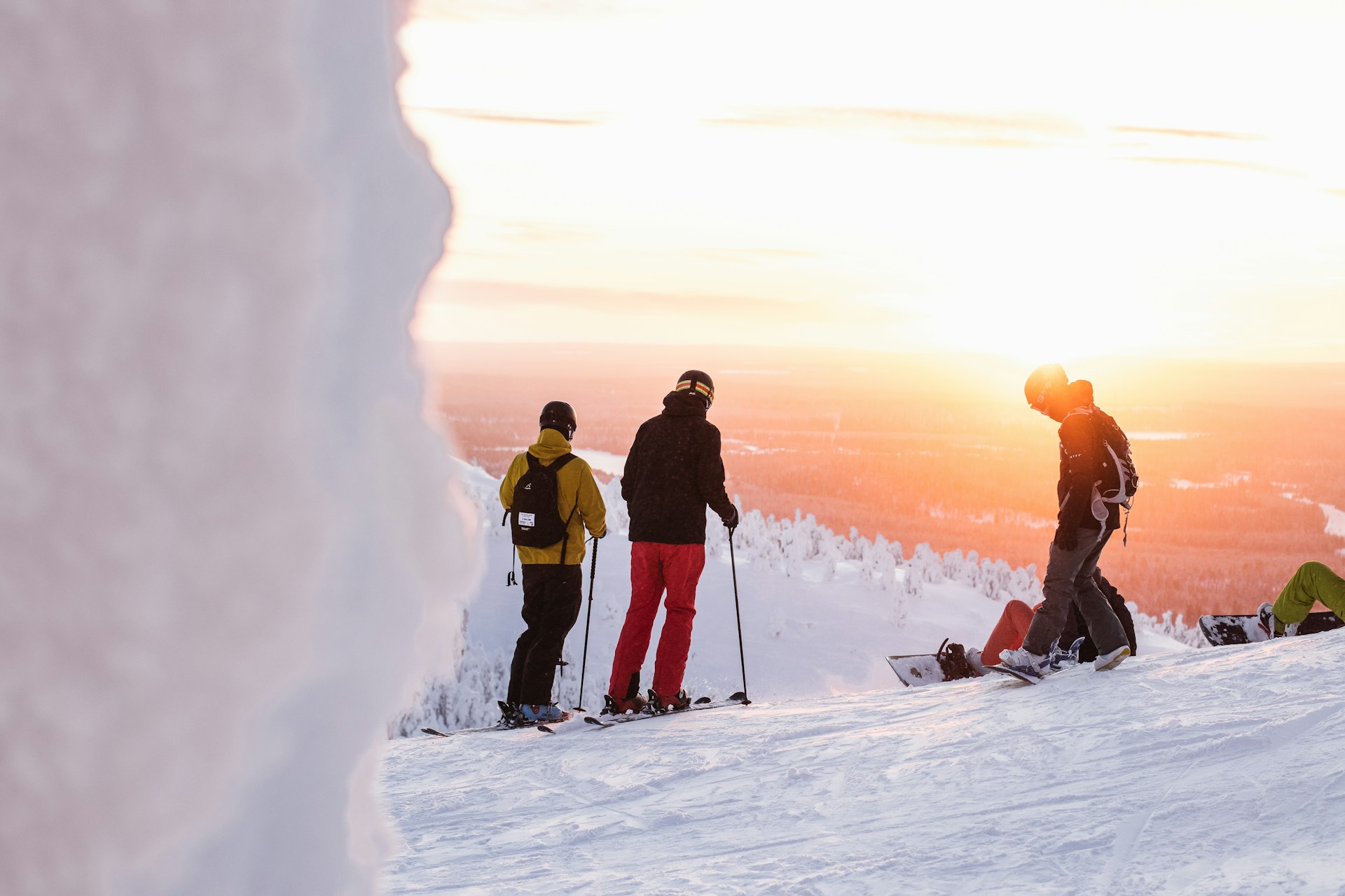 A family laughing and skiing down a snowy slope, bundled up in bright winter gear against a backdrop of frosted trees.